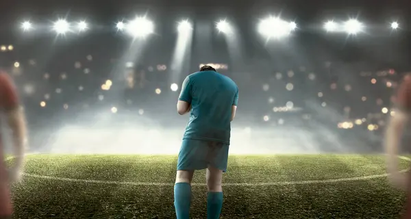 男子足球运动员在球场上以聚光灯背景庆祝获胜的肖像 图库图片