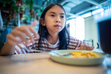 Restoranda sosis yiyen Asyalı küçük kız.