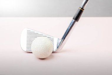 Yerde golf sopası olan bir golf topunun yakın görüntüsü.