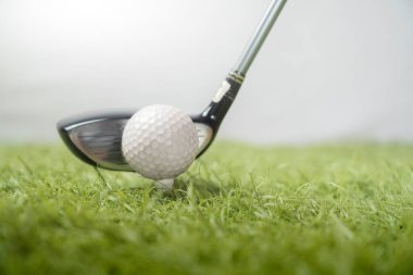 Golf topunun golf sahasındaki yakın görüntüsü, golf sopası salıncak için konumlandırılmış, golf topunun dokusuna odaklanmış, bulanık doğal bir arka plan.
