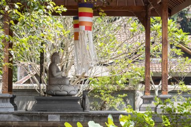 Candi Mendut, Magelang, Endonezya - 22 Mayıs 2024. Buddha 'nın taş heykeli parktaki ağaçlarla çevrili köşkte.