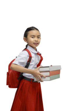 Asyalı bir ilkokul öğrencisinin portresi. Sırt çantalı, beyaz arka planda izole bir kitap yığını taşıyordu.