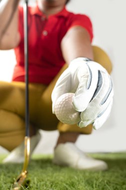 Eldivenli bir golfçü sahadaki golf topuna vuruyor.