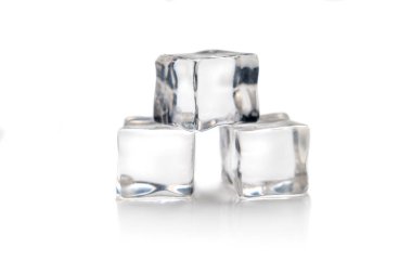 Üç buz kübü üst üste narin bir şekilde dengede duruyor, parlak beyaz bir yüzeyde minyatür bir kule yaratıyor, ışıkta parlıyor ve serinlemek için yavaşça eriyor.