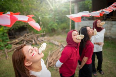 Endonezyalı kadınların portresi Endonezya Bağımsızlık Günü 'nü dışarıda kraker yeme yarışması gibi geleneksel etkinliklerle kutluyor.