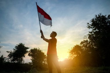 Endonezya bayrağını elinde tutan bir adamın portresi.