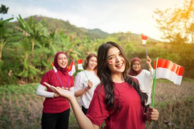 Heyecanlı yüz ifadeleri olan bir grup kadın ellerinde küçük bir Endonezya bayrağı tutuyorlardı.