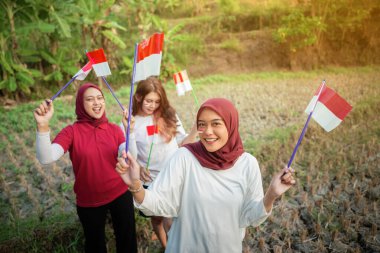 Heyecanlı yüz ifadeleri olan bir grup kadın ellerinde küçük bir Endonezya bayrağı tutuyorlardı.