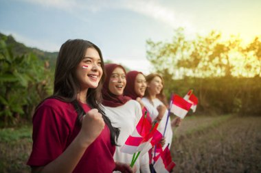 Heyecanlı yüz ifadeleri olan bir grup kadın ellerinde küçük bir Endonezya bayrağı tutuyorlardı.