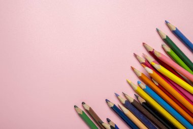 Pembe arka planda bir sıra renkli kalem. Kalemler sıraya dizilmiştir, bazıları diğerlerinden daha uzundur. Yaratıcılık ve sanatsal ifade kavramı