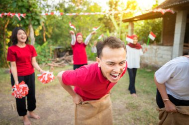 Bir grup insan çuval yarışı oynuyor. Sahne neşeli ve eğlenceli, bir grup insan gülüyor ve eğleniyor. Endonezya 'nın bağımsızlık günü kavramı