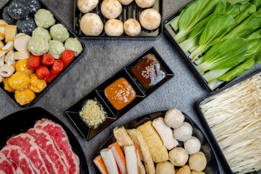 Et, sebze ve deniz ürünleri de dahil olmak üzere çeşitli gıda ürünleri bir masada sergilenmektedir. Sunum renkli ve iştah açıcı, dokular ve tatlar karışımı.