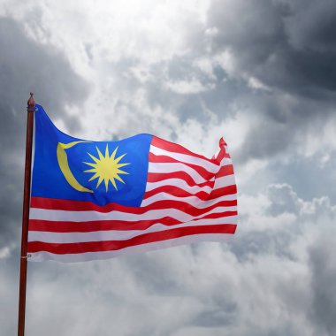 Sarı yıldızlı ve kırmızı çizgili bir Malezya bayrağı rüzgarda dalgalanıyor. Gökyüzü bulutlu ve güneş görünmüyor.