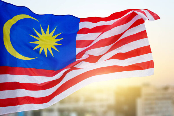 В воздухе развевается флаг Малайзии с синей звездой и красными полосами