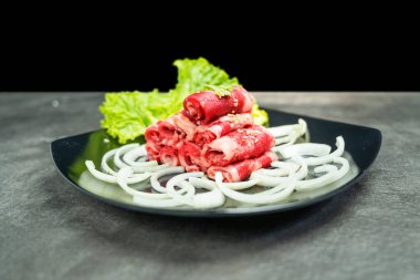 Üstünde soğan ve marul olan bir tabak et.