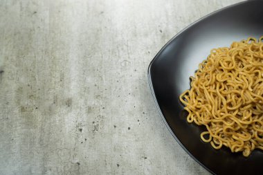 Bir tabak hazır şehriye masanın üzerinde duruyor. Erişteler uzun ve ince ve tabakta üst üste yığılmış. Bolluk ve hoşgörü kavramı