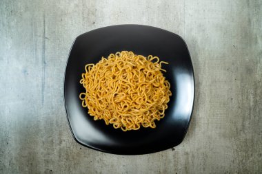 Bir tabak hazır şehriye masanın üzerinde duruyor. Erişteler uzun ve ince ve tabakta üst üste yığılmış. Bolluk ve hoşgörü kavramı