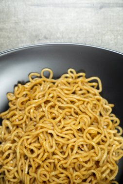 Bir tabak hazır şehriye masanın üzerinde duruyor. Erişteler uzun ve ince ve tabakta üst üste yığılmış. Bolluk ve hoşgörü kavramı