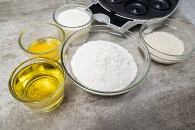 İçinde un, şeker ve yağ bulunan bir kaç kase malzeme olan bir masa. Kadehler üst üste dizilir, kuru malzemeler içeren kaseler ve sıvılar içerir.