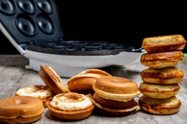 Bir yığın çörek ve gözleme ızgarası. Çörekler üst üste yığılmış ve waffle ızgarası da arka planda. Hoşgörü ve rahatlık kavramı