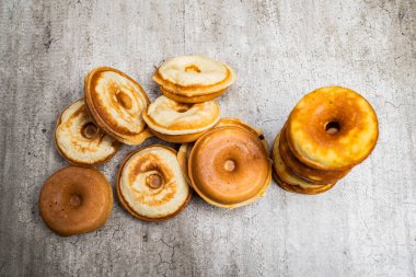 Çeşit çeşit tatları ve boyutları olan bir yığın çörek. Hoşgörü ve keyif kavramı, çörekler üst üste yığılmış ve yenmeye hazır.