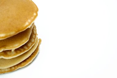 Beyaz arka planda bir yığın krep. Krepler altın kahverengidir ve taze yapılmış gibi görünüyor. Sıcaklık ve rahatlık kavramı, çünkü krepler genellikle kahvaltıyla ilişkilendirilir.