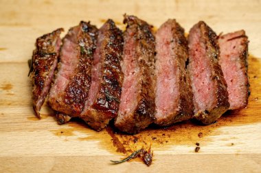 Bir parça fileto altı parçaya bölünmüş ve ahşap bir kesme tahtasının üzerinde oturuyor. Et kahverengi ve çıtır çıtır bir dokusu var. Memnuniyet ve başarı kavramı