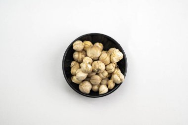 Beyaz arka planda bir kase Java kakule duruyor. Fındıklar küçük ve yuvarlak ve kasenin her tarafına saçılmış. Kase temiz, seyircinin içindeki cevizleri görmesini sağlıyor.