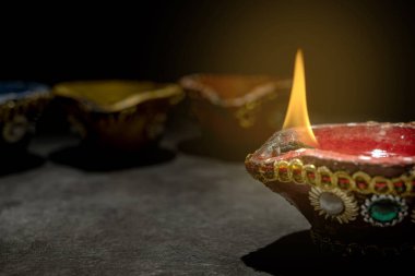 Bir sıra küçük kırmızı ve mavi mum, sıcak ve davetkar bir atmosfer yaratıyor. Mumlar daire şeklinde dizilir, içlerinden biri daha büyük bir alevle, dikkatleri üzerine çeker. Diwali konsepti