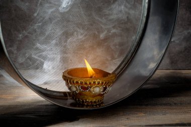 Diya oil lamp on the sieve. The candle is lit and the light is shining through the mesh, creating a warm and cozy atmosphere. Karva Chauth festival concept clipart