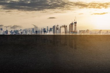 Arka planda önplanda büyük boş bir boşluk ile bir şehir silueti gösterilir. Gökyüzü bulutlu ve güneş batıyor.