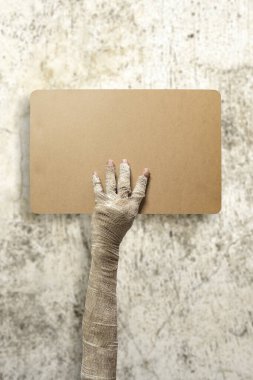 Mumya ellerinin üzerinde kirli bandaj var. Mumya, şeytan, şeytan, şeytan ya da zombi elleri kirli duvar arkası olan boş bir kağıt parçası tutuyor. Modelleme. Uzayı kopyala Ürkütücü Cadılar Bayramı konsepti