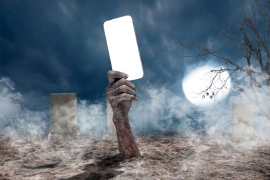 Kanlı bir yara almış zombi eli cep telefonu ya da cep telefonu tutarak yerden kalkıyor. Kopya alanı için boş cep telefonu ekranı. Zombi, şeytan, şeytan, şeytan ya da canavar eller. Ürkütücü Cadılar Bayramı konsepti