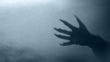 Mavi arka planda kürklü ve siyah pençeli kurt adam elleri. El uzanıyor ve gölge kararıyor. Korkunç kurt adam pençesi, kurt adam ya da hayvan canavarı. Ürkütücü Cadılar Bayramı konsepti