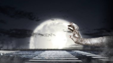 Mumya eli bandajlı ve dolunay arkaplanlı. Sahne karanlık ve korkutucu. Şeytan, şeytan, şeytan, zombi ya da canavar eli gibi görünen bir el. Ürkütücü Cadılar Bayramı konsepti