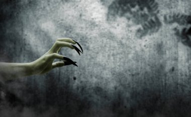 Uzun tırnak pençeli cadılar elini uzatıyor. Rengi yeşil. Karanlık bir odada kötülük, zombi ya da canavar eli gösteriliyor. Sahne korkutucu ve ürkütücü. Ürkütücü Cadılar Bayramı konsepti