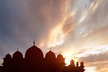 Günbatımı sahnesinde bulutlar olan bir caminin silueti. İslam dini, Ramazan kareemi veya Kurban Bayramı geçmişi