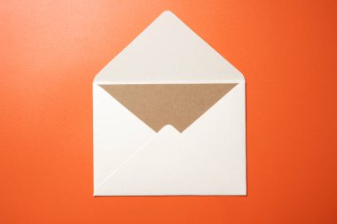 Beyaz zarf ve renkli arkaplanda boş kahverengi kart olan kartpostalın üst görüntüsü. Model, kopyalama alanı. Düz yatış biçimine sahip tebrik ya da davet kartı