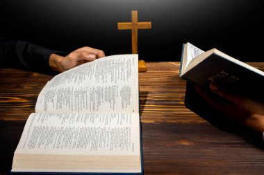 Din haçı ve açık bir İncil 'in üzerinde birlikte dua eden bir adam. İnancın ve Tanrı 'ya tapmanın sembolü. Kilisedeki insanlar Hıristiyanlık duası. Dini hizmet, tatil veya konsept