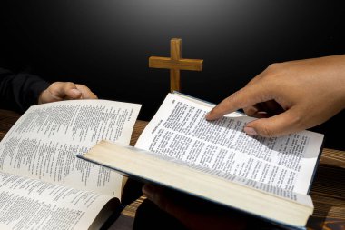 Din haçı ve açık bir İncil 'in üzerinde birlikte dua eden bir adam. İnancın ve Tanrı 'ya tapmanın sembolü. Kilisedeki insanlar Hıristiyanlık duası. Dini hizmet, tatil veya konsept