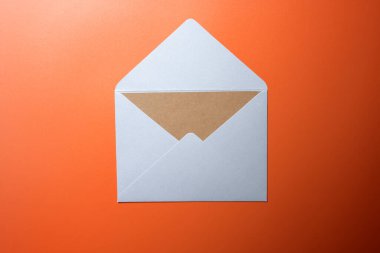 Beyaz zarf ve renkli arkaplanda boş kahverengi kart olan kartpostalın üst görüntüsü. Model, kopyalama alanı. Düz yatış biçimine sahip tebrik ya da davet kartı