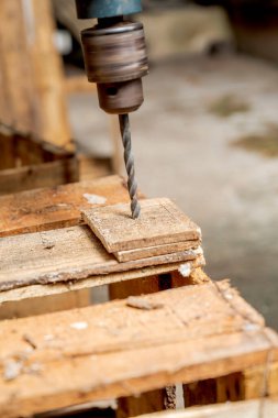 Güvenlik yeleği ve eldiven giyen işçiler atölyede odun talimi yapıyorlar. Sahne deponun arka planında geçiyor. Ahşap fabrikası