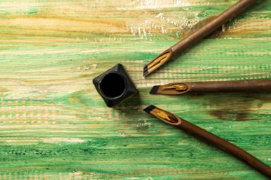 Kaligrafi kamışları ahşap arka planda mürekkeple kaplıydı. Arapça yazı yazmak için sazlıklar kalem mürekkebi