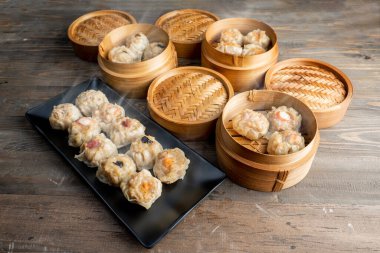 Tabakta Çin Dim Sum köftesi ve ahşap masada bambu ahşap sepet kasesi. Kahvaltı, öğle yemeği ya da akşam yemeği. Çin ya da Ay Yeni Yıl Dekorasyonu