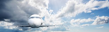 Gökyüzünde uçan ticari uçağın arka planında bulutlar var. Uçak konseptiyle seyahat