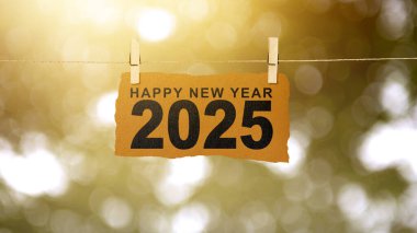 Mutlu Yeni Yıl 2025 metni soyut bokeh ışık arkaplanlı asma kağıda yazılmış. Mutlu yıllar konsepti ya da kutlama