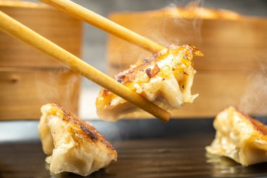 Çubuklu insan eli kızarmış Çin mantısı, gyoza, jiaozi veya mandu yer. Kahvaltı, öğle yemeği ya da akşam yemeği. Çin ya da Ay Yeni Yıl Dekorasyonu