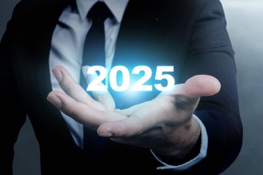 Avucunun içinde 2025 numaranın olduğu bir el var. Mutlu yıllar konsepti ya da kutlama