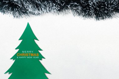 Ahşap bir Noel ağacı süslemesinin yakın plan görüntüsü. Beyaz arka planda Mutlu Noeller ve Mutlu Yıllar metni. Noel ve Yeni Yıl kutlamaları için dekorasyon