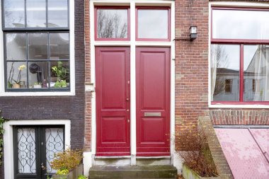 Evin ön cephesi merdivenli ve cam pencereli Amsterdam, Hollanda 'da kırmızı bir ön kapısı var. İnşaat ve mimari arka plan